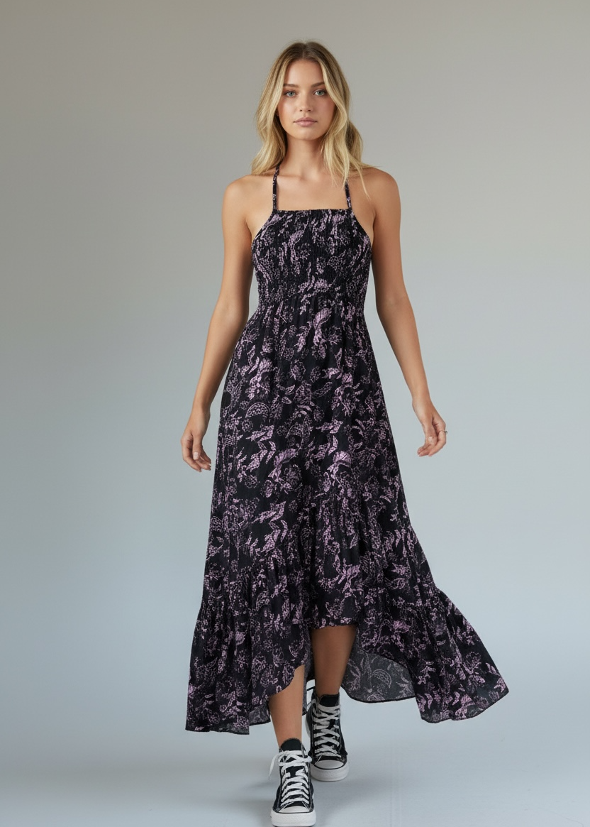 Woman wearing a long, patterned dress with high-low hem on a plain background