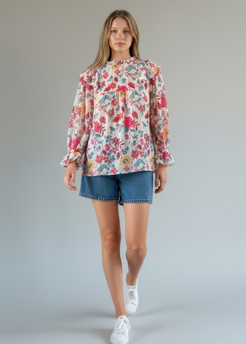 Woman wearing a floral blouse and denim shorts on a plain background