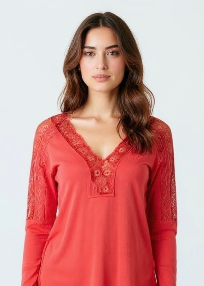Woman wearing a red lace-trimmed top against a white background