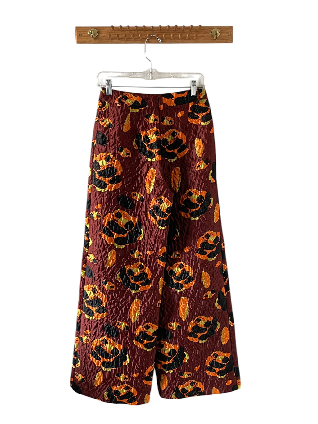 Wide-leg pants with pumpkin pattern on a hanger against a white background