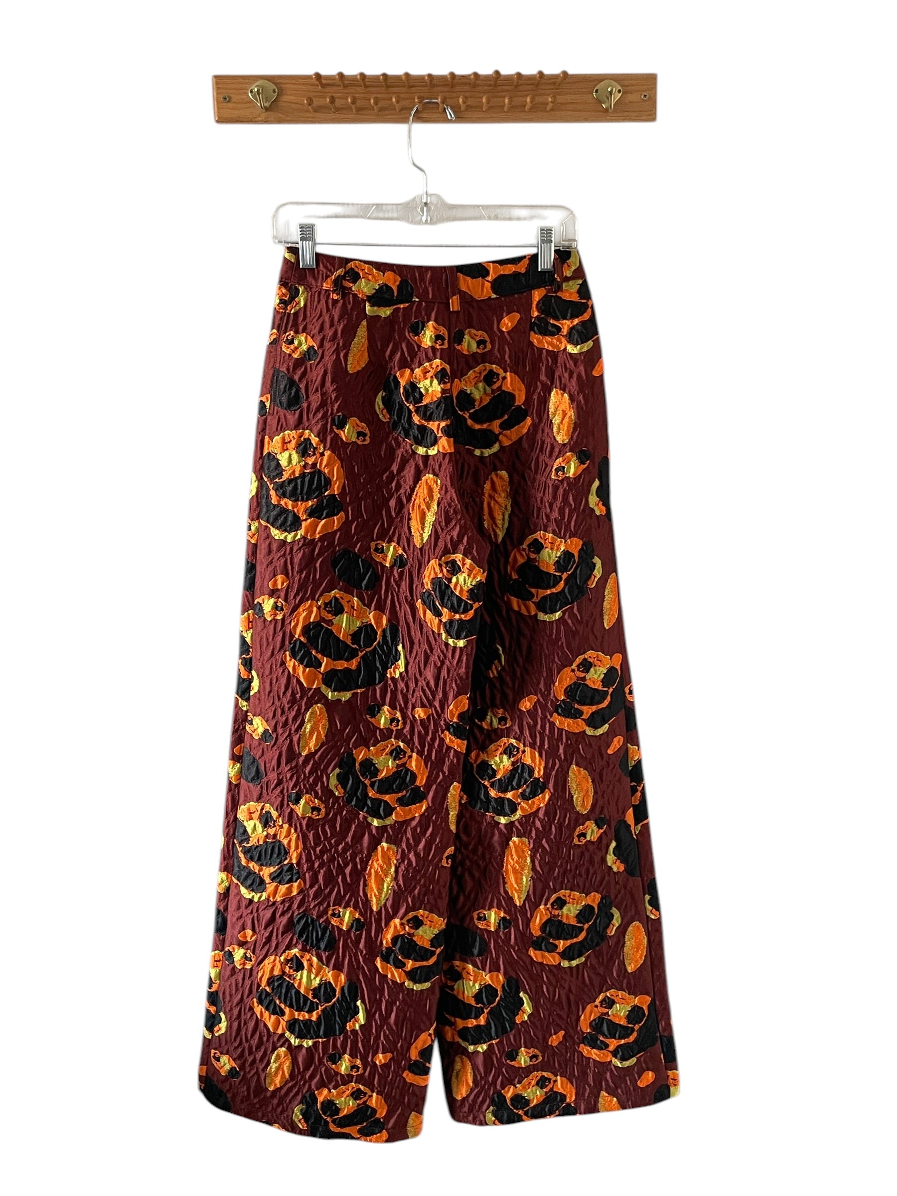Wide-leg pants with pumpkin pattern on a hanger against a white background