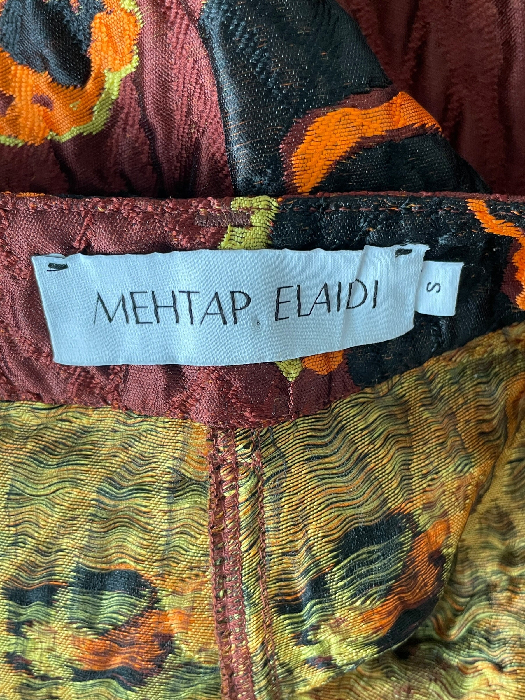Close-up of a colorful fabric with a brand label reading 'MEHTAP ELAIDI'.