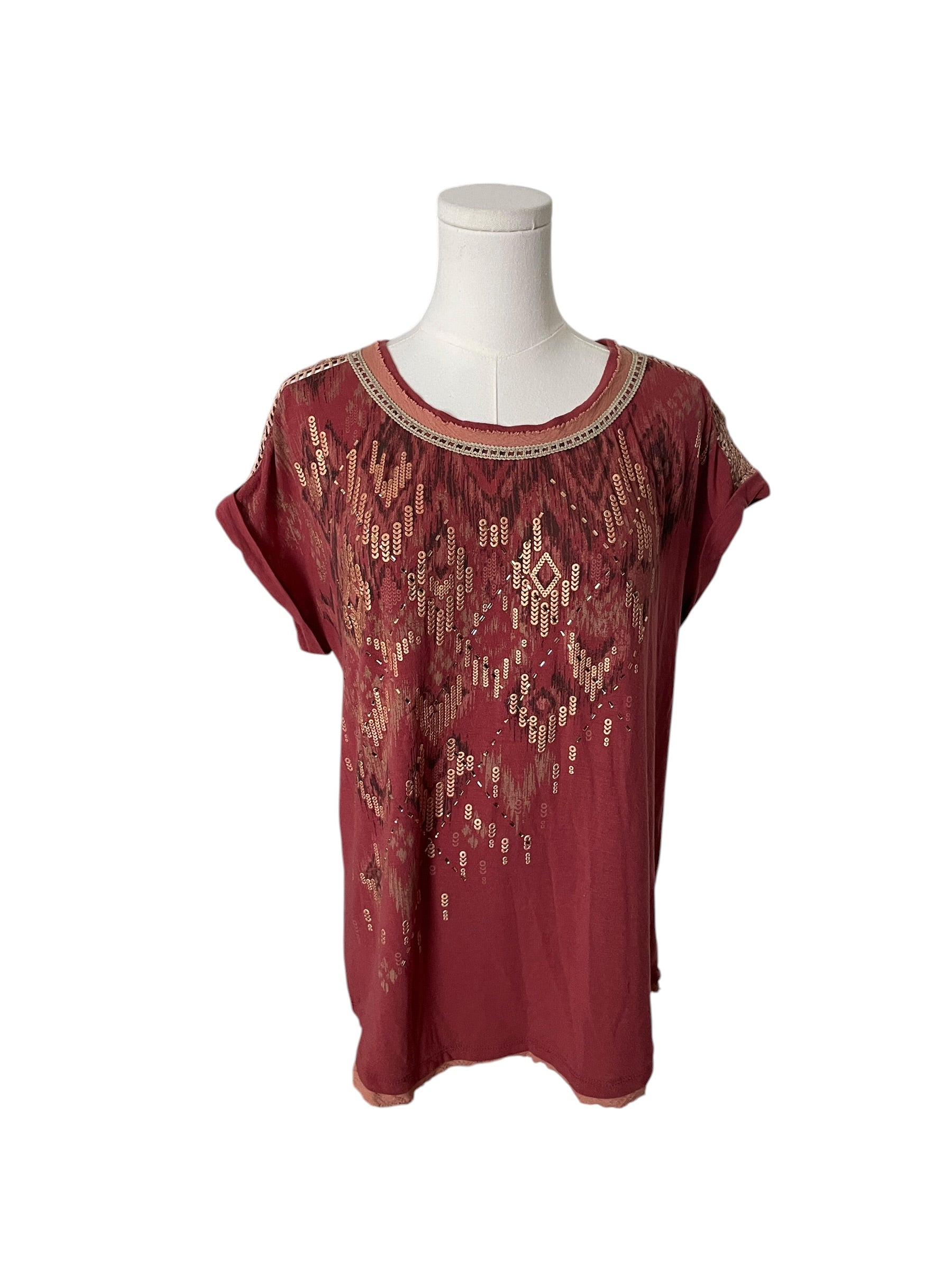 Red blouse with gold patterns on a mannequin against a white background