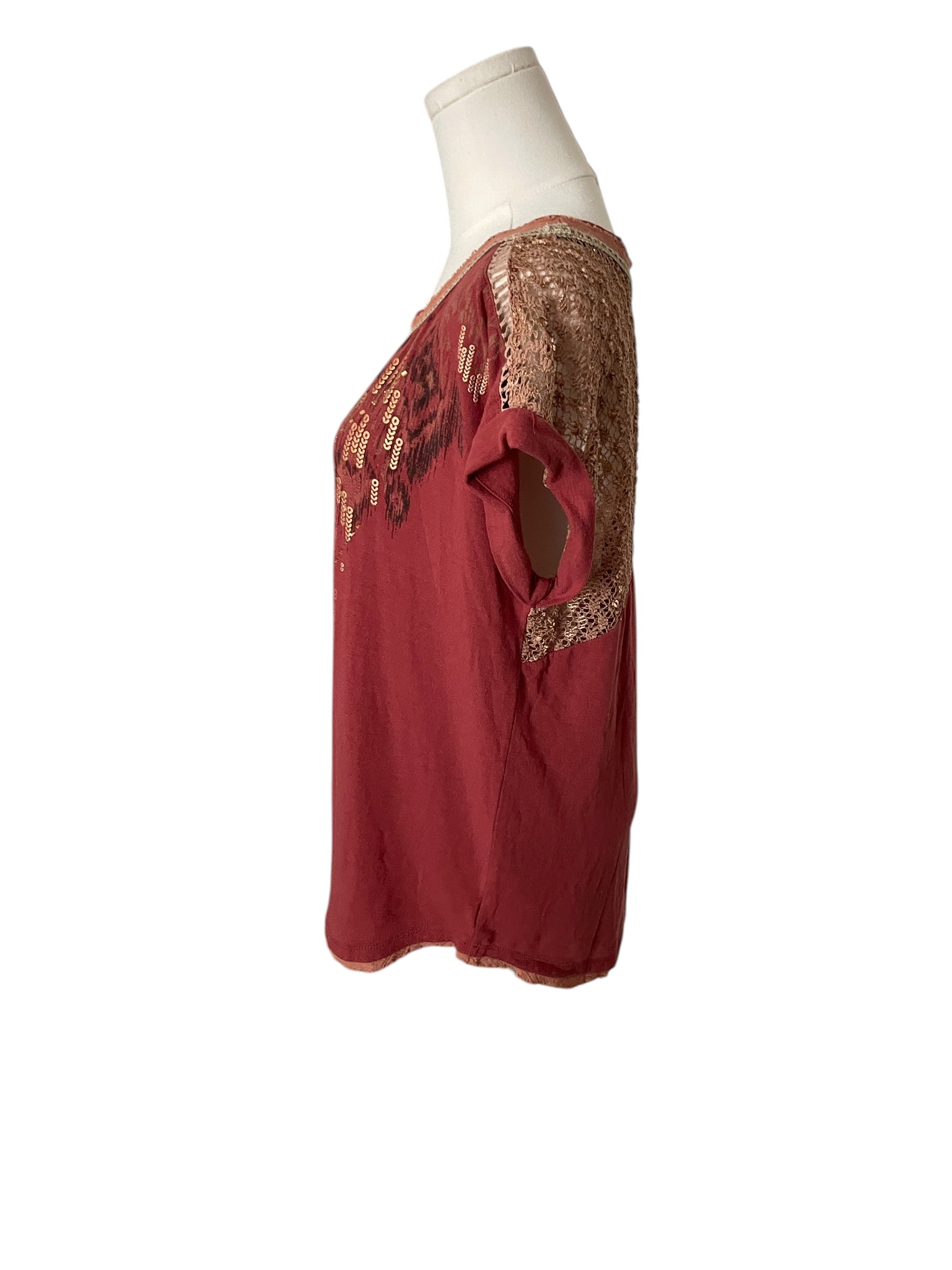 Red blouse with gold lace details on a mannequin against a white background