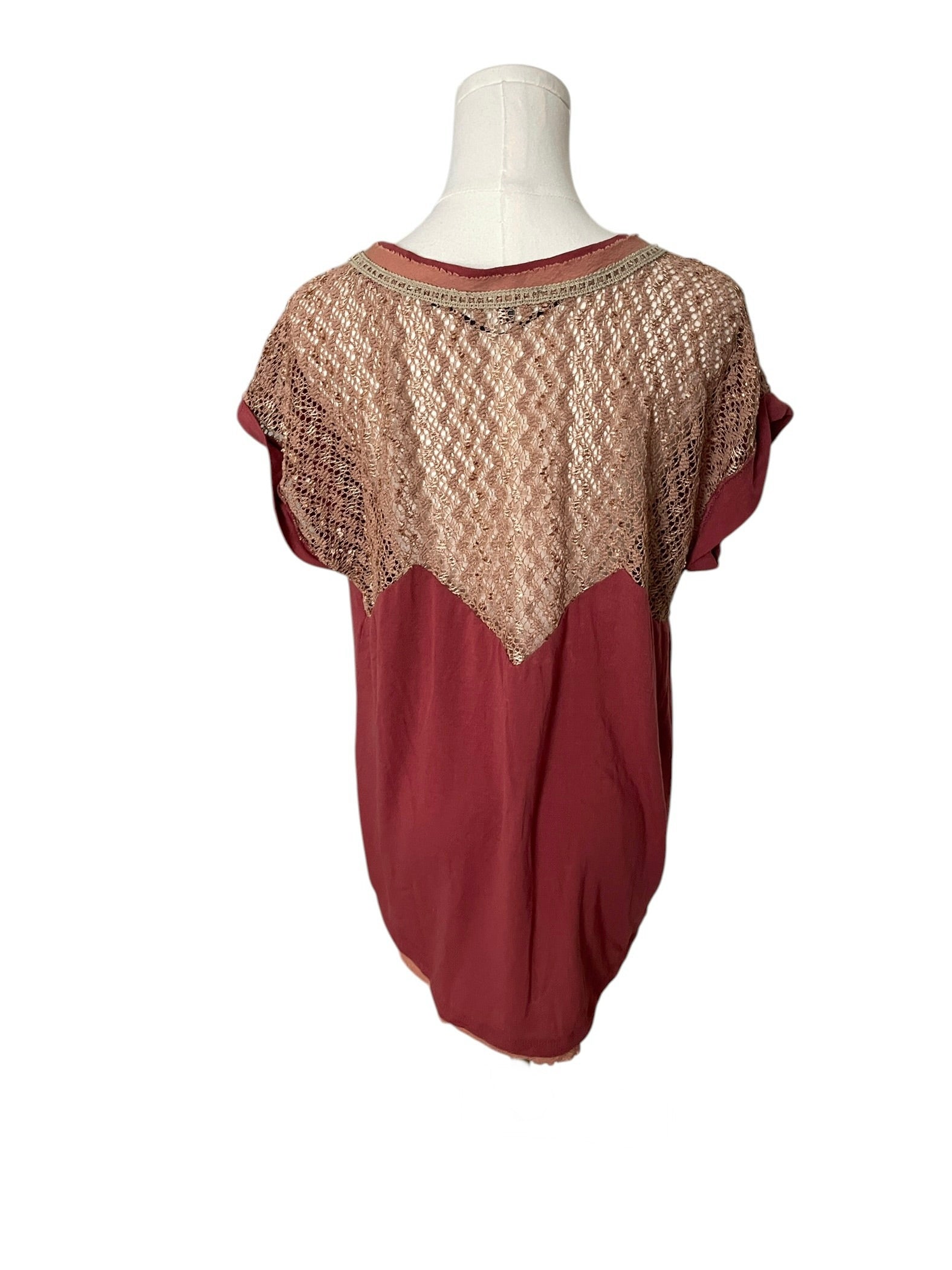 Red blouse with lace detailing on a mannequin against a white background