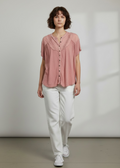 Person wearing a pink blouse and white pants against a plain background