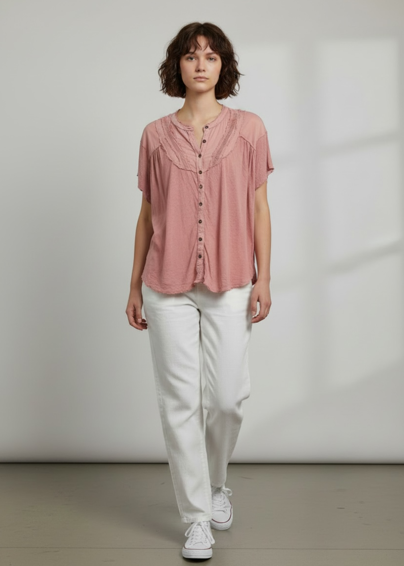 Person wearing a pink blouse and white pants against a plain background