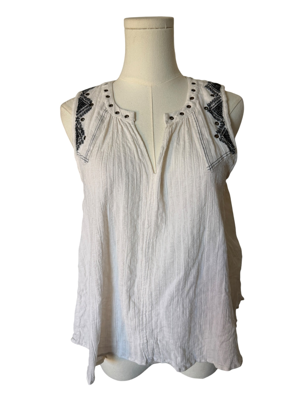 White sleeveless top with black lace details on a mannequin against a white background