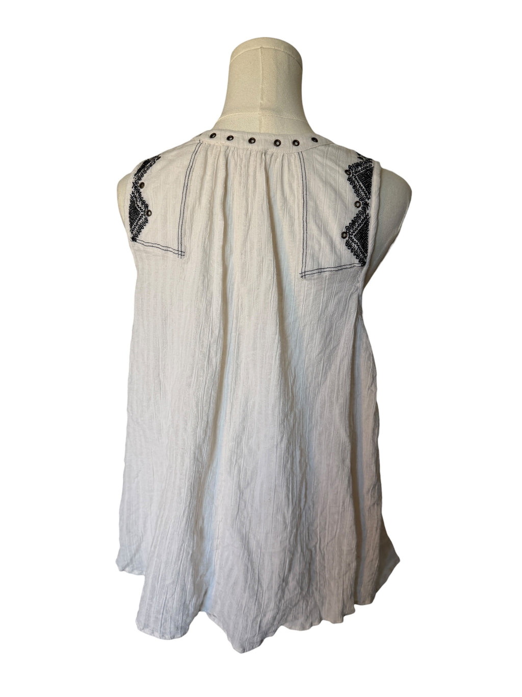 White sleeveless top with black embroidery on a mannequin against a white background