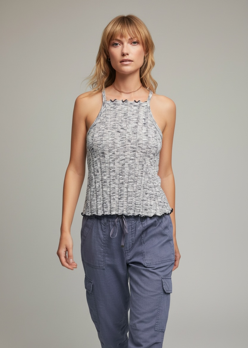 Woman wearing a patterned tank top and blue cargo pants on a gray background