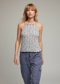 Woman wearing a patterned tank top and blue cargo pants on a gray background