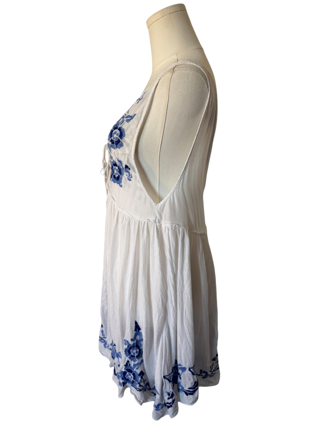 White dress with blue floral patterns on a mannequin against a white background
