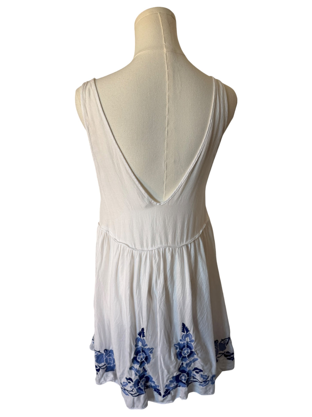 White dress with blue floral patterns on a mannequin against a white background