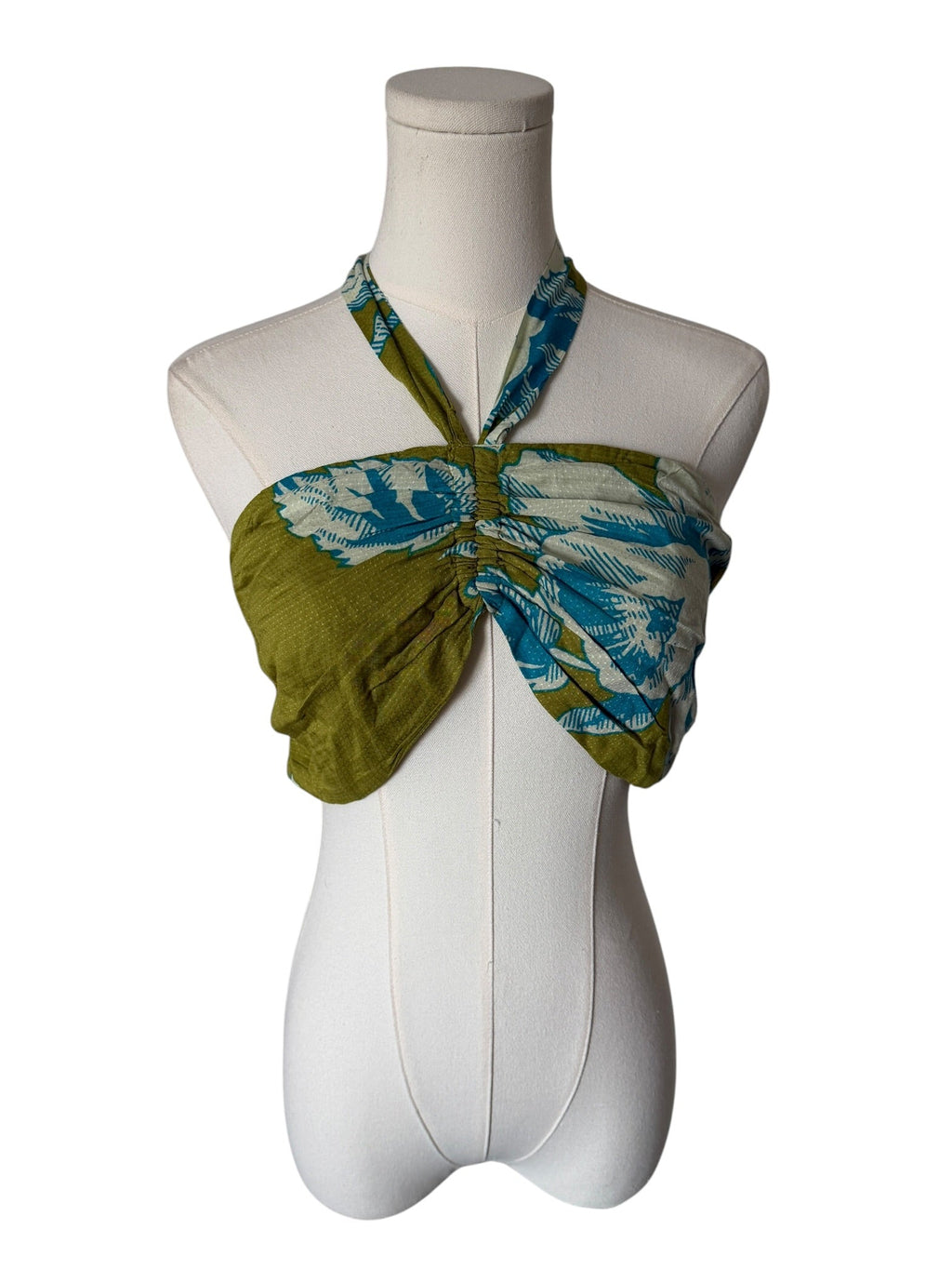 Green and blue patterned scarf tied around a mannequin on a white background