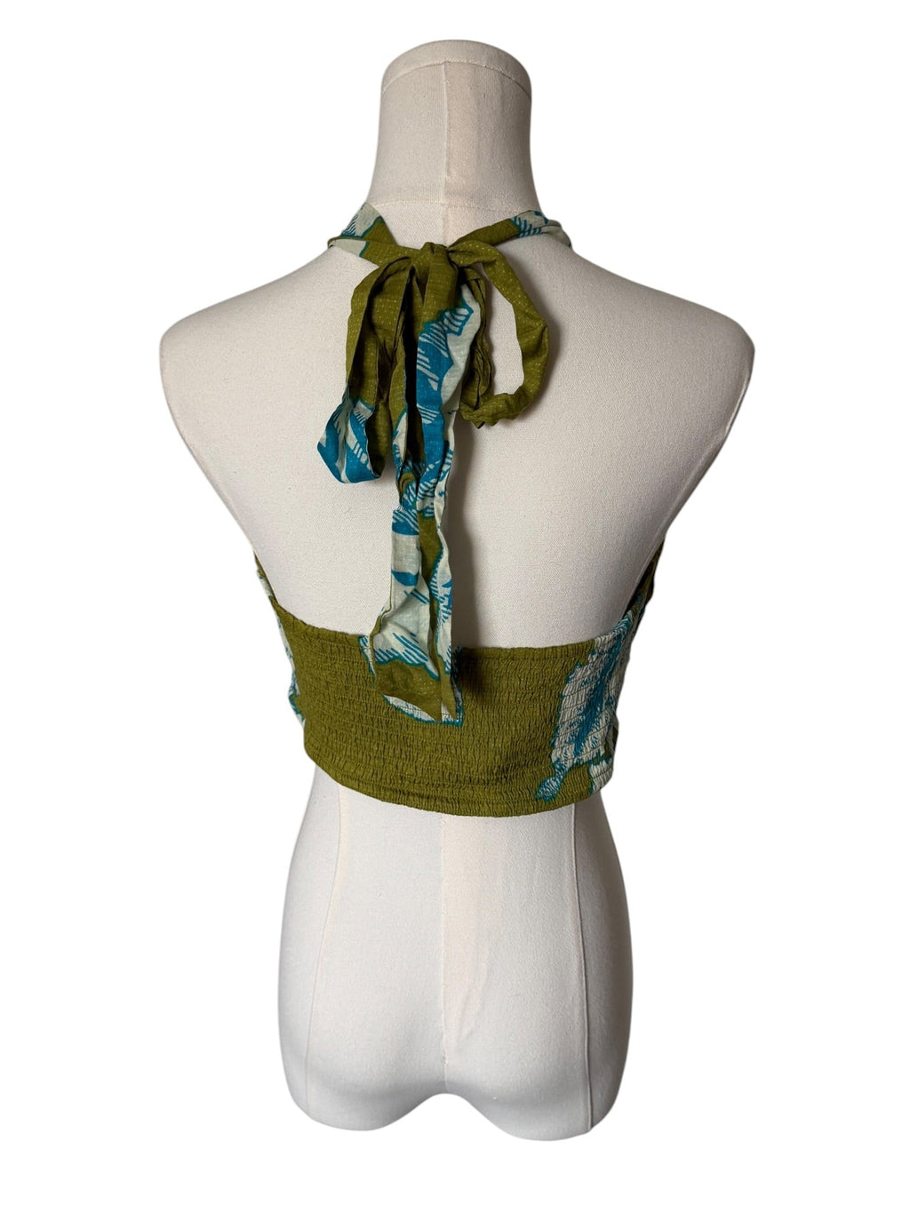 Green halter top with a scarf on a mannequin against a white background