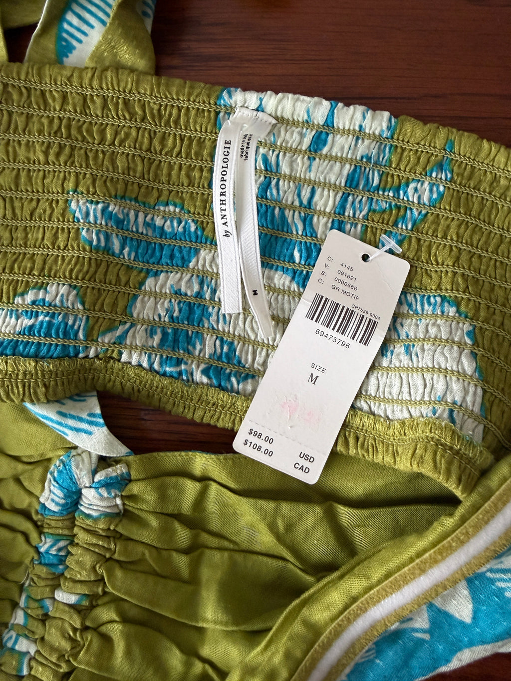 Green fabric with blue and white patterns and a visible tag on a wooden surface