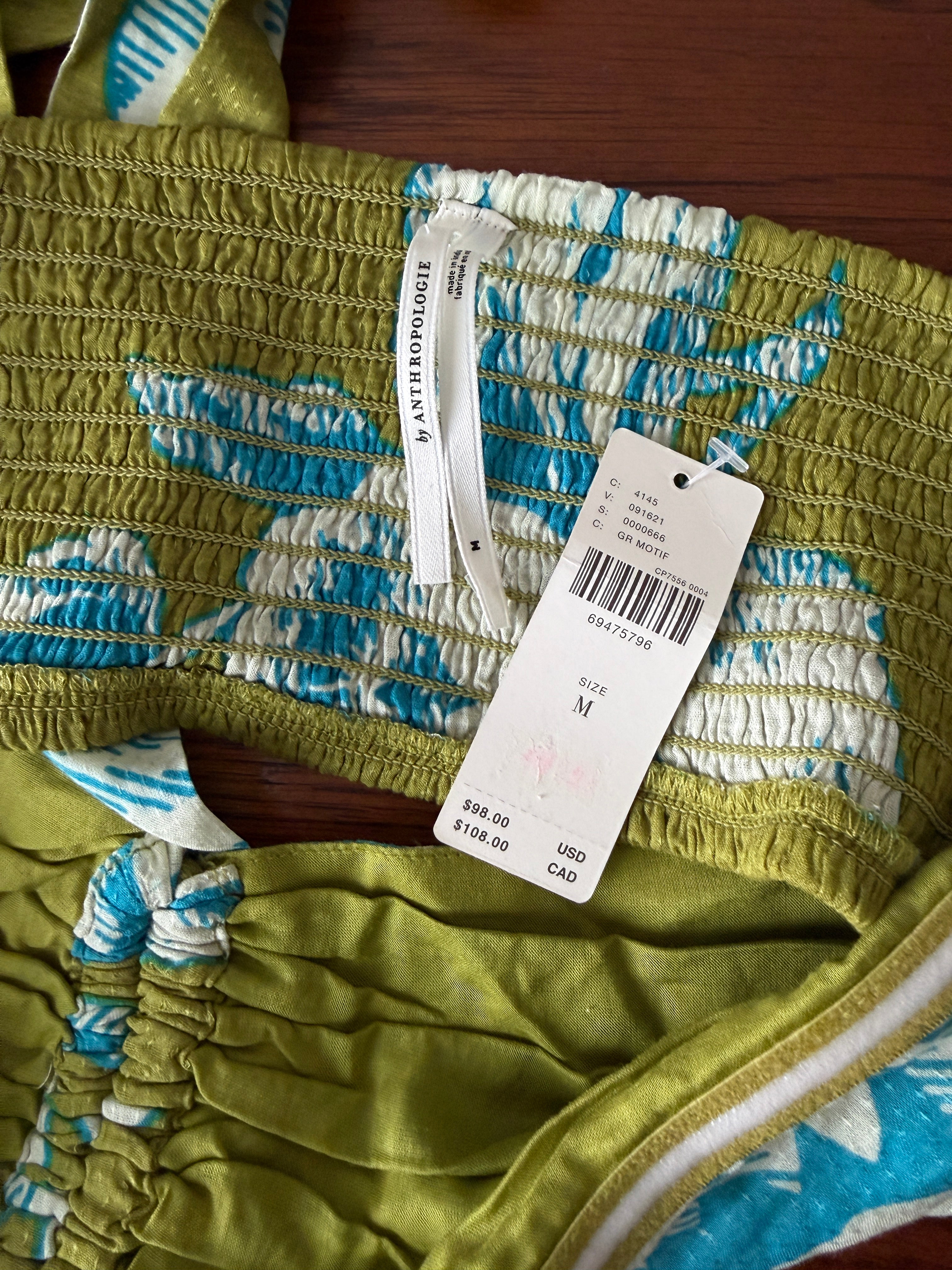 Green fabric with blue and white patterns and a visible tag on a wooden surface