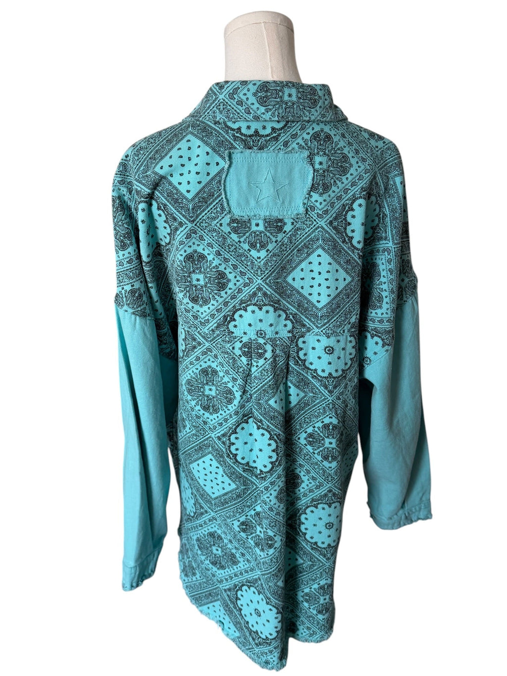 Teal patterned shirt on a mannequin against a white background