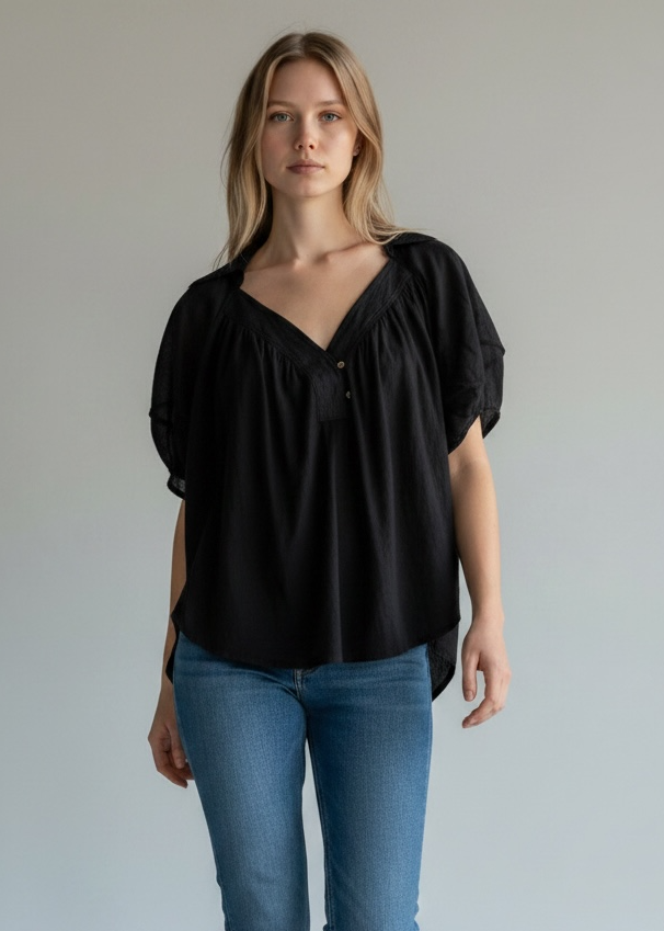 Woman wearing a black top and blue jeans against a plain background