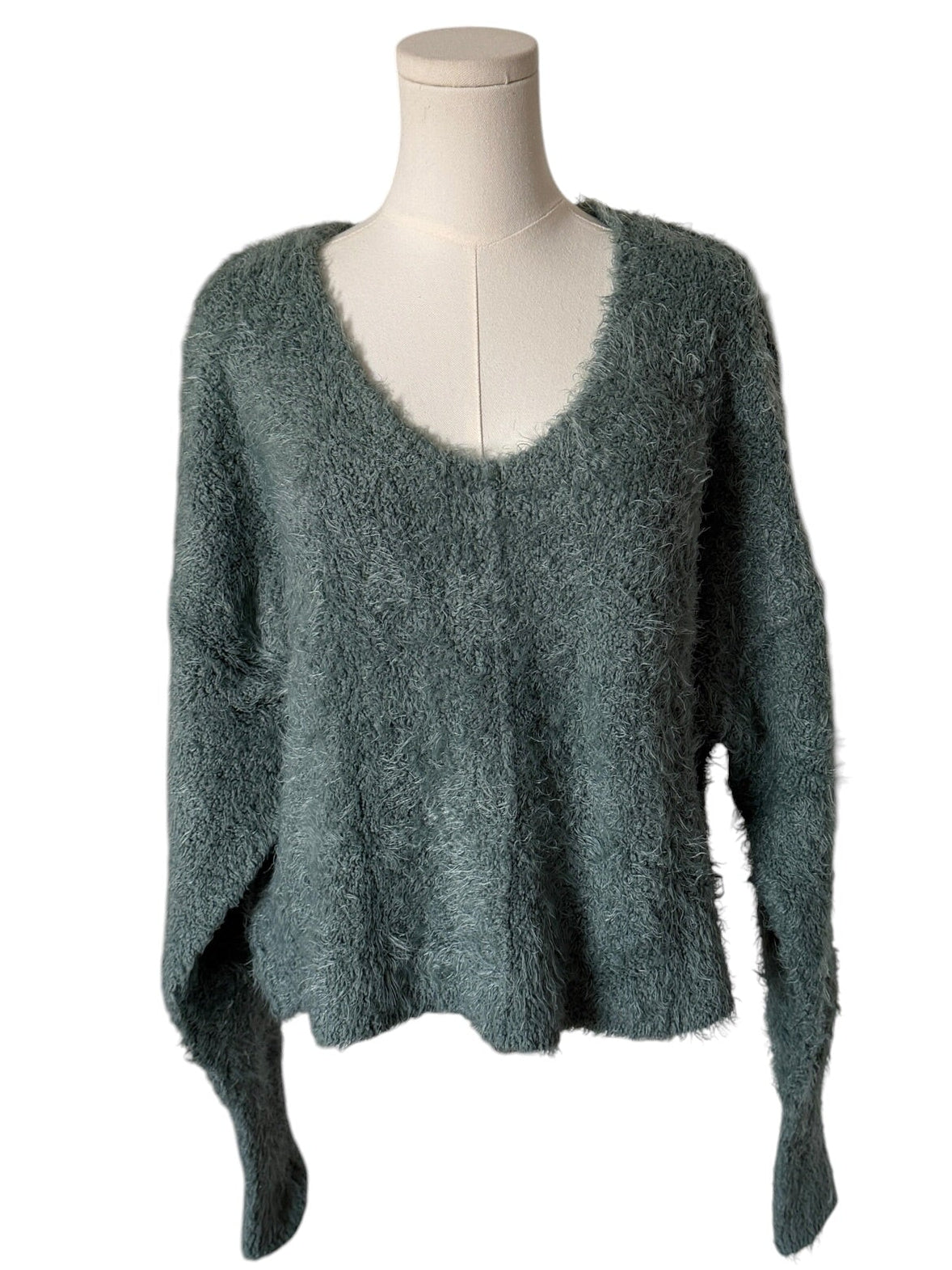Green sweater on a mannequin against a white background