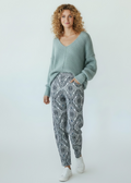 Woman wearing a light blue sweater and patterned pants on a white background