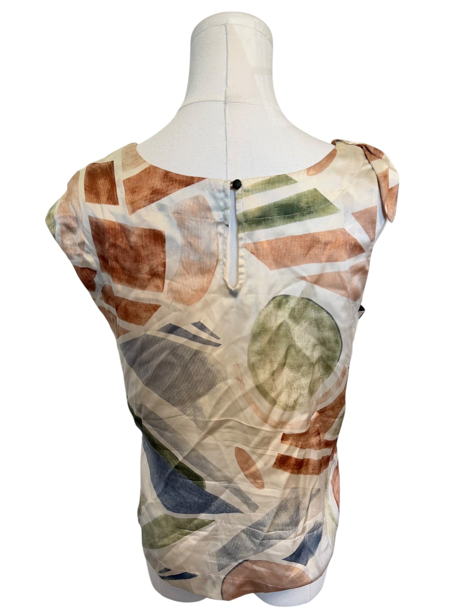 Mannequin wearing a sleeveless top with a leaf pattern on a white background