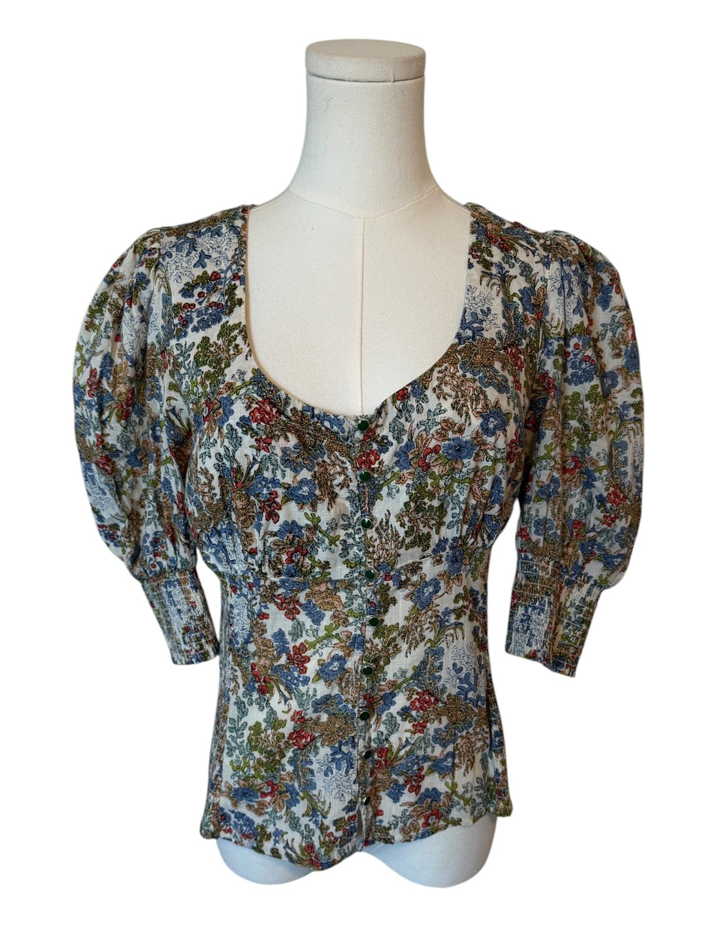 Floral patterned blouse on a mannequin against a white background