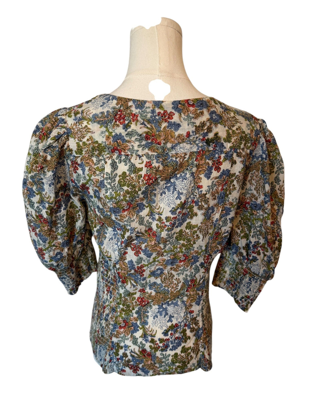 Floral blouse on a mannequin against a white background