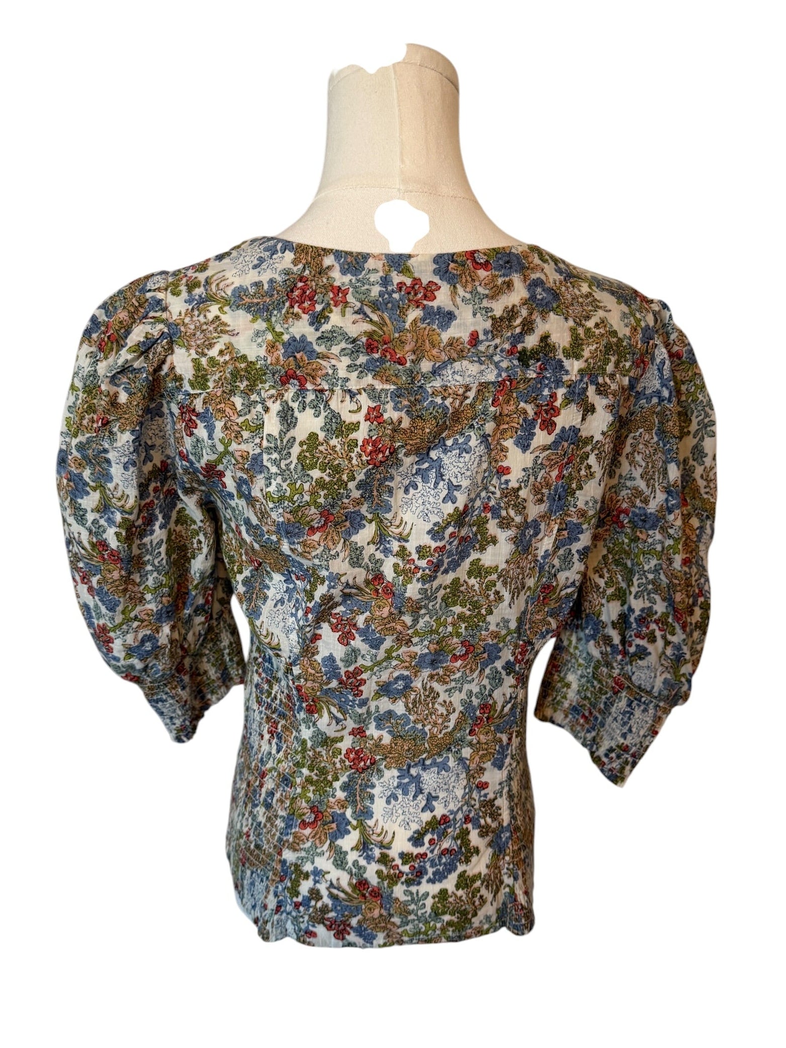 Floral blouse on a mannequin against a white background