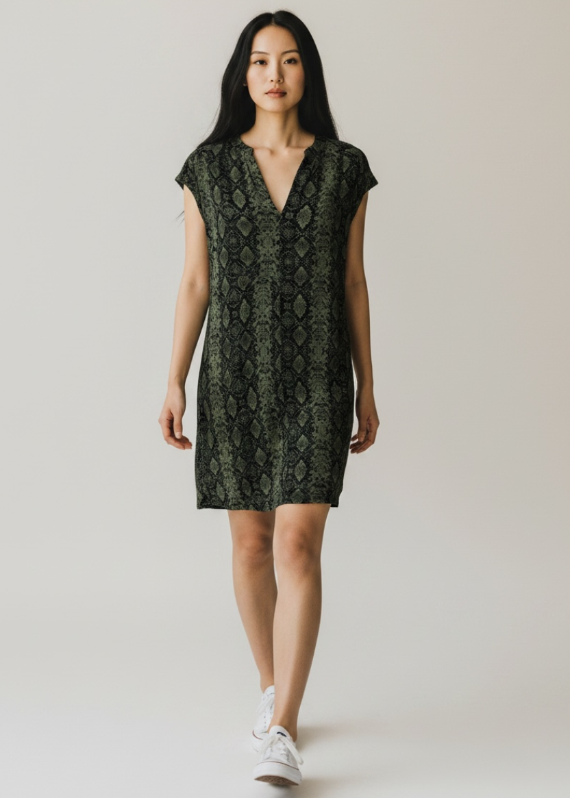 Woman wearing a green patterned dress on a plain background