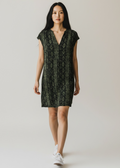 Woman wearing a green patterned dress on a plain background