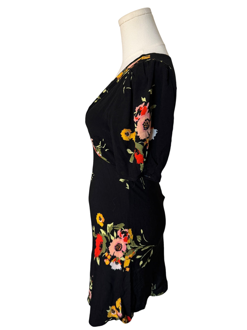 Black dress with colorful floral embroidery on a mannequin against a white background