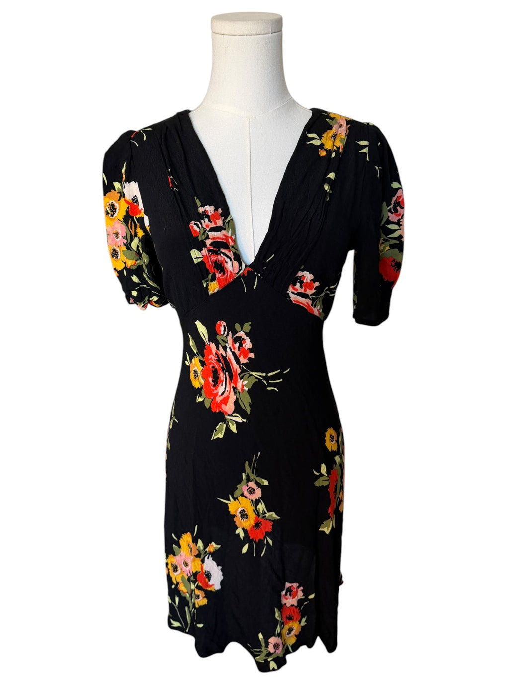 Black dress with colorful floral pattern on a mannequin against a white background