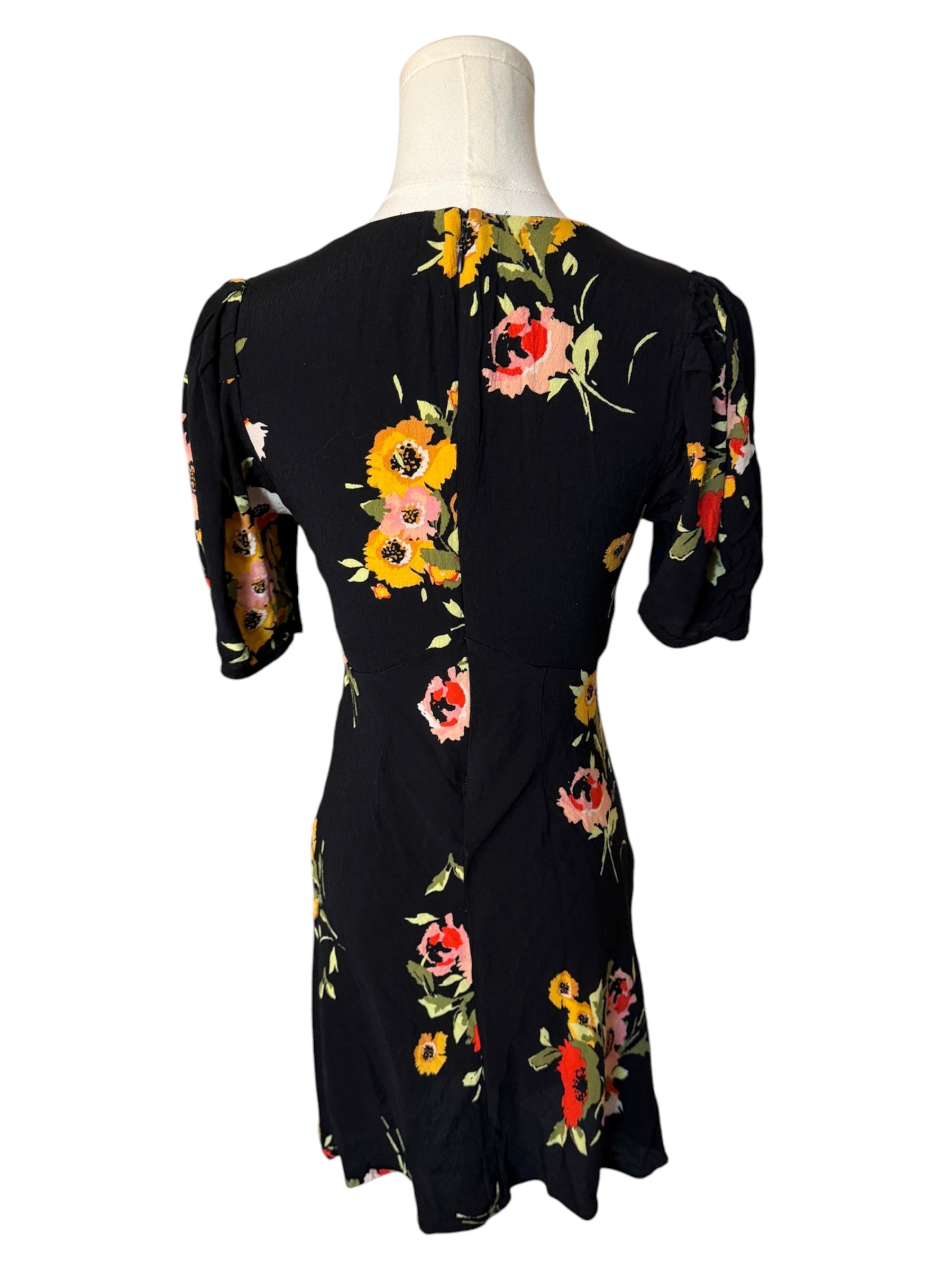 Black dress with colorful floral pattern on a mannequin against a white background