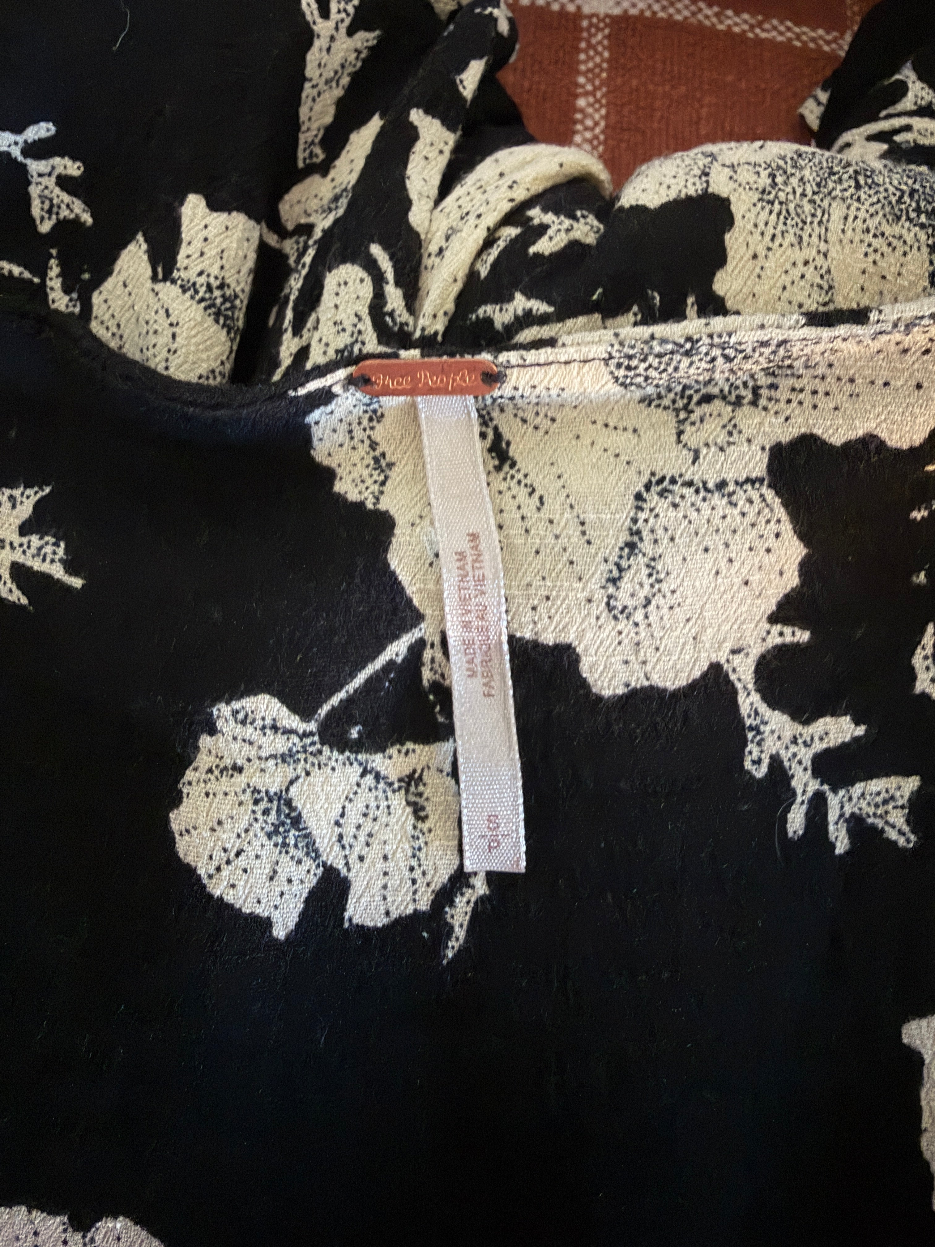 Black fabric with white floral pattern and a visible brand tag.