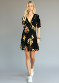 Woman wearing a black floral dress against a gray background