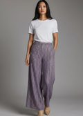 Woman wearing a white t-shirt and patterned purple pants on a gray background