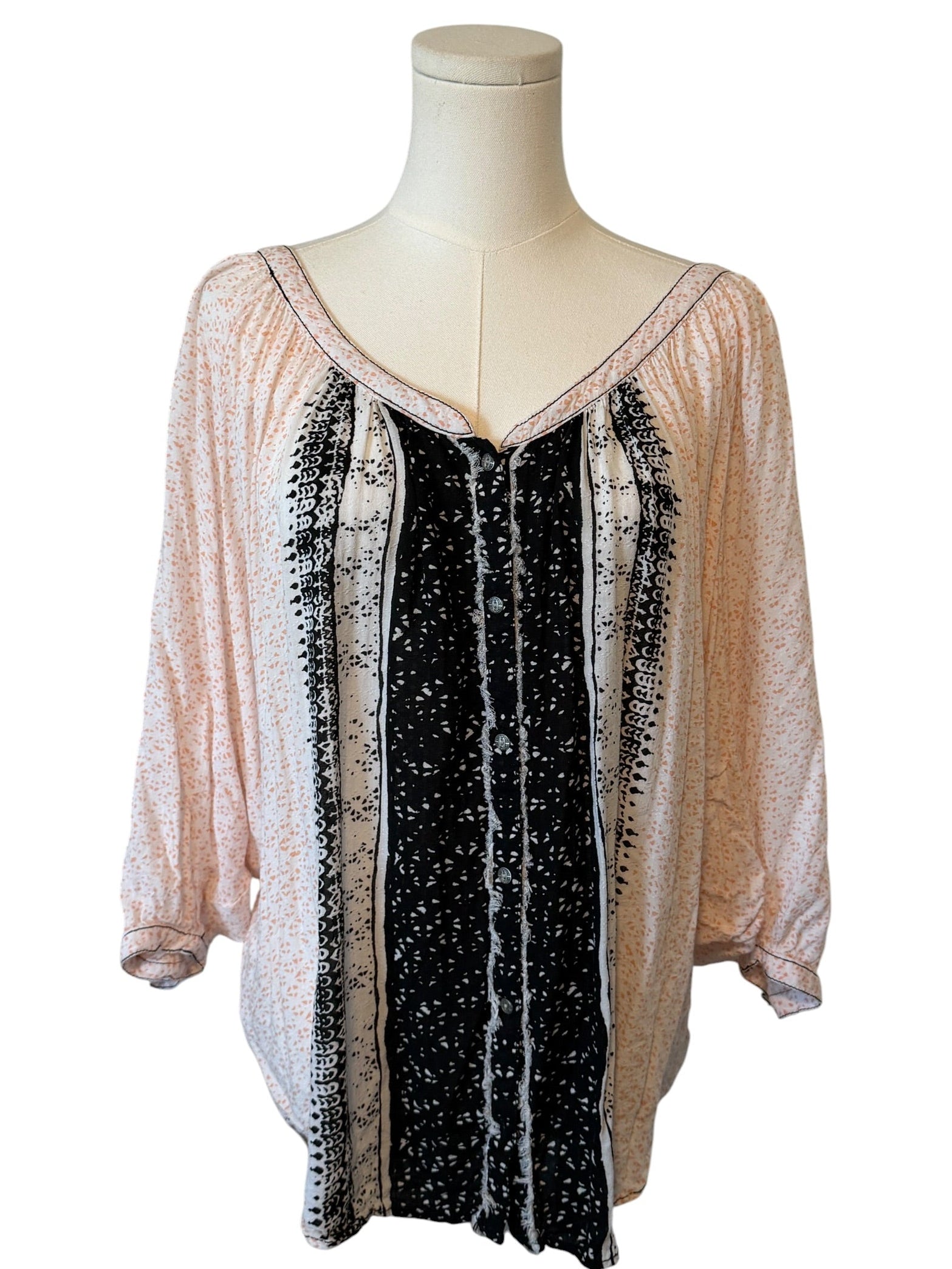 Mannequin wearing a two-tone blouse with pink and black patterns on a white background