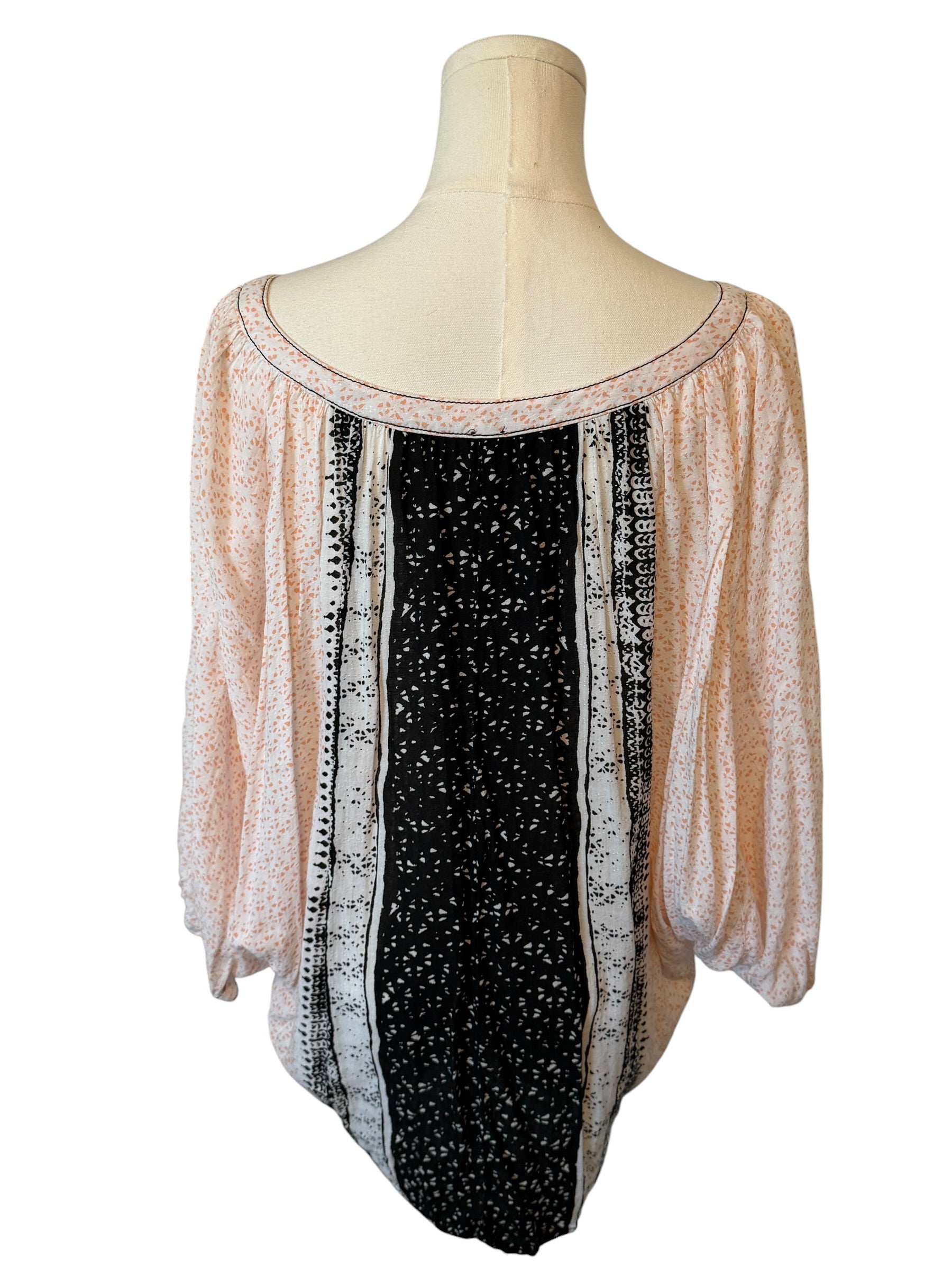 Mannequin wearing a long-sleeve top with a black and white pattern on a white background