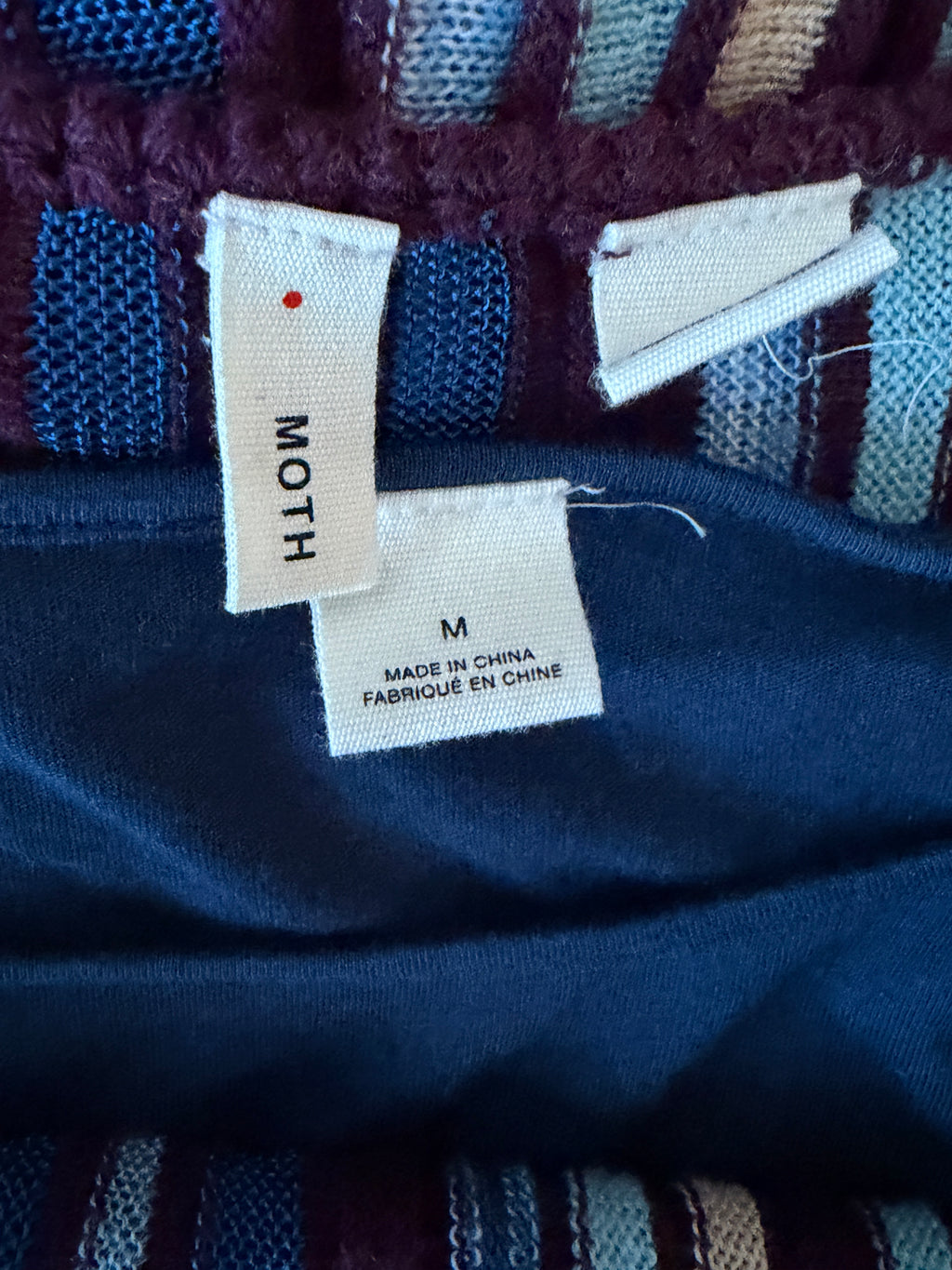 Close-up of a blue fabric with 'MOTH' label and 'Made in China' label.