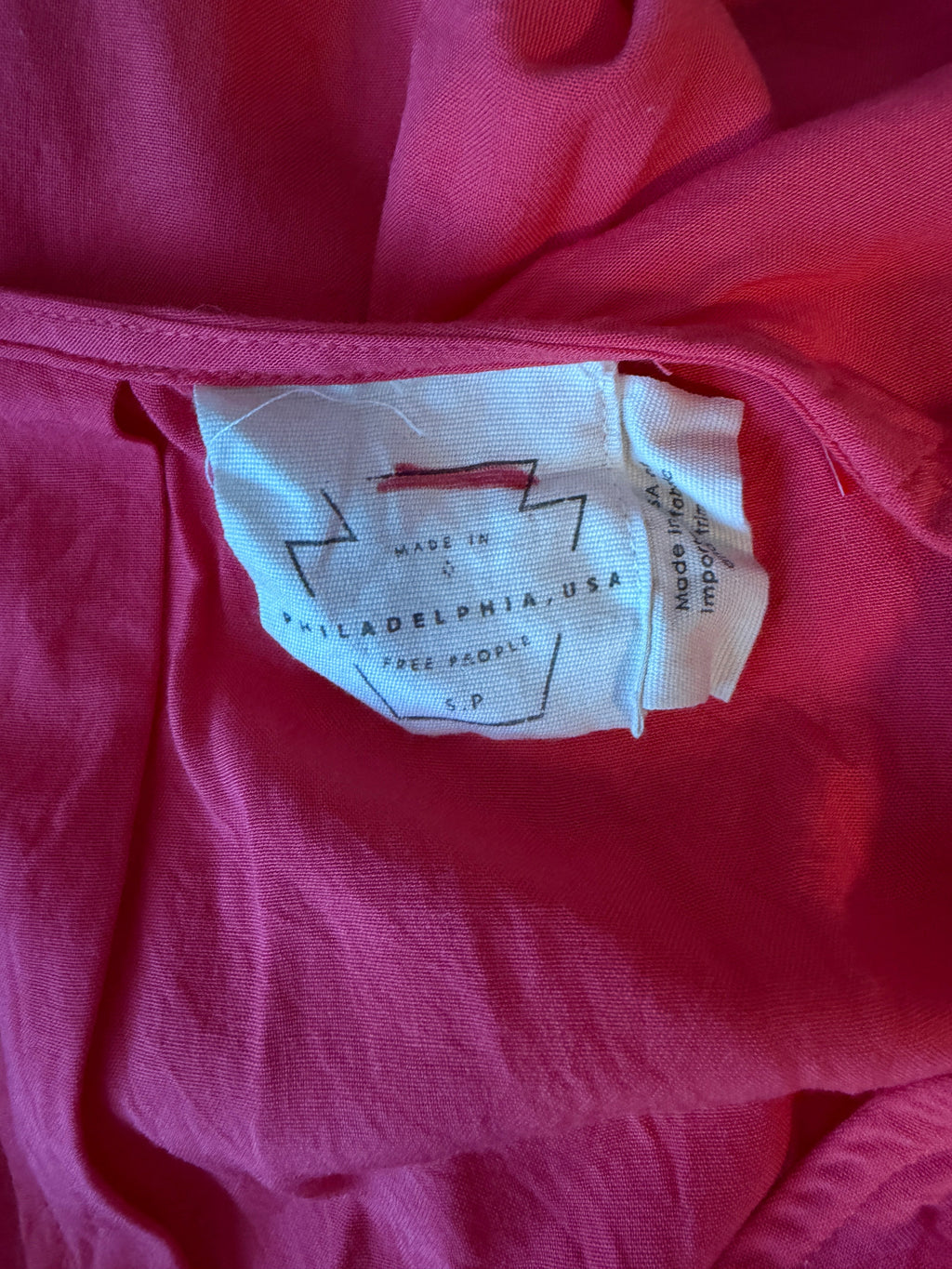 Close-up of a red garment with a label on a pink background