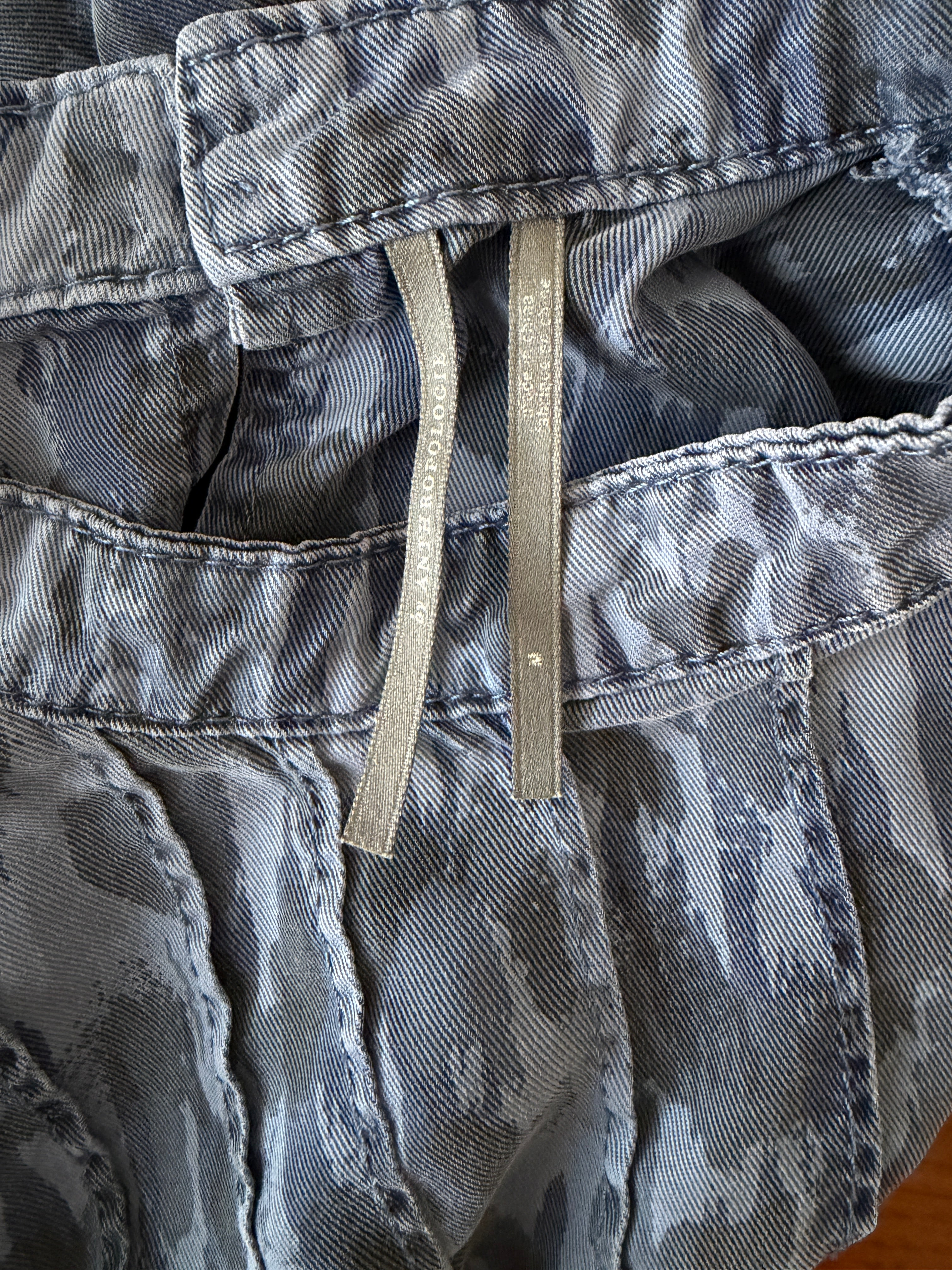 Close-up of a camouflage jacket with brand labels on a wooden surface