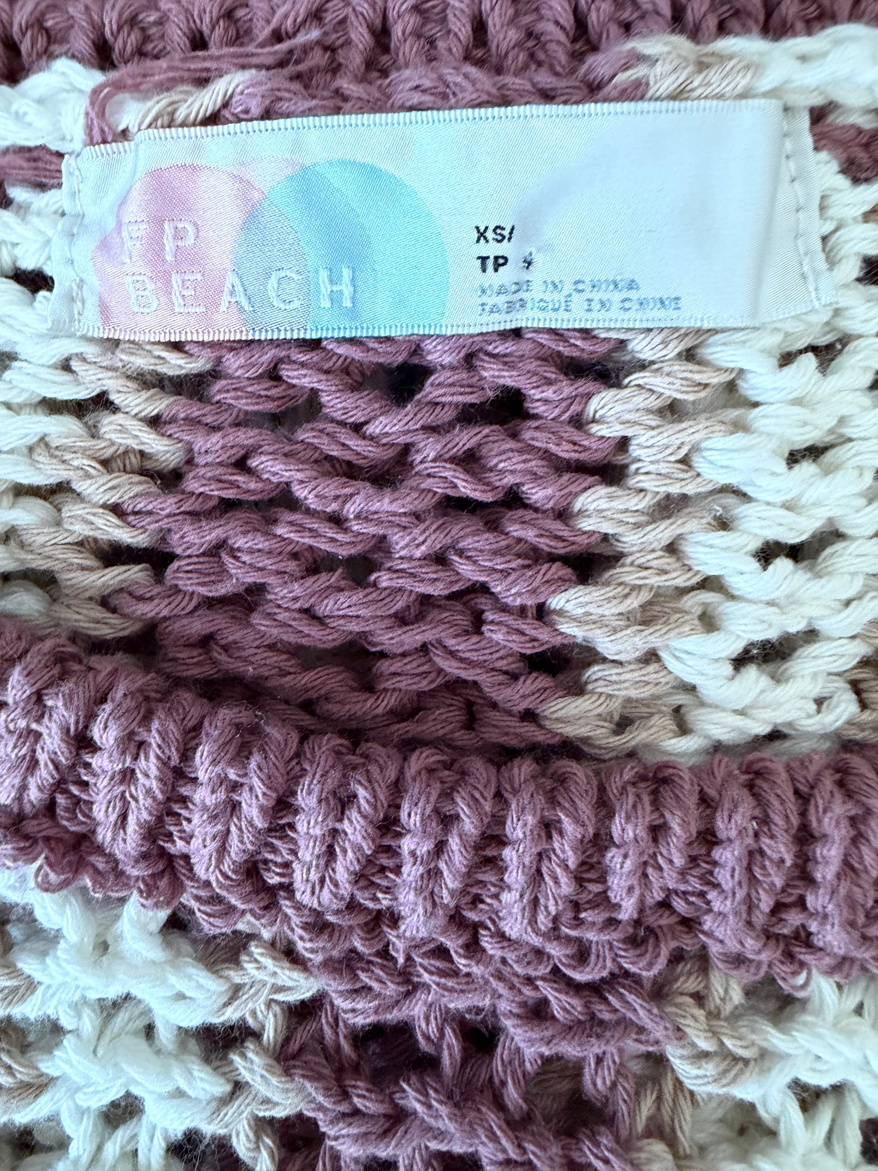 Close-up of a crocheted top with a brand tag.