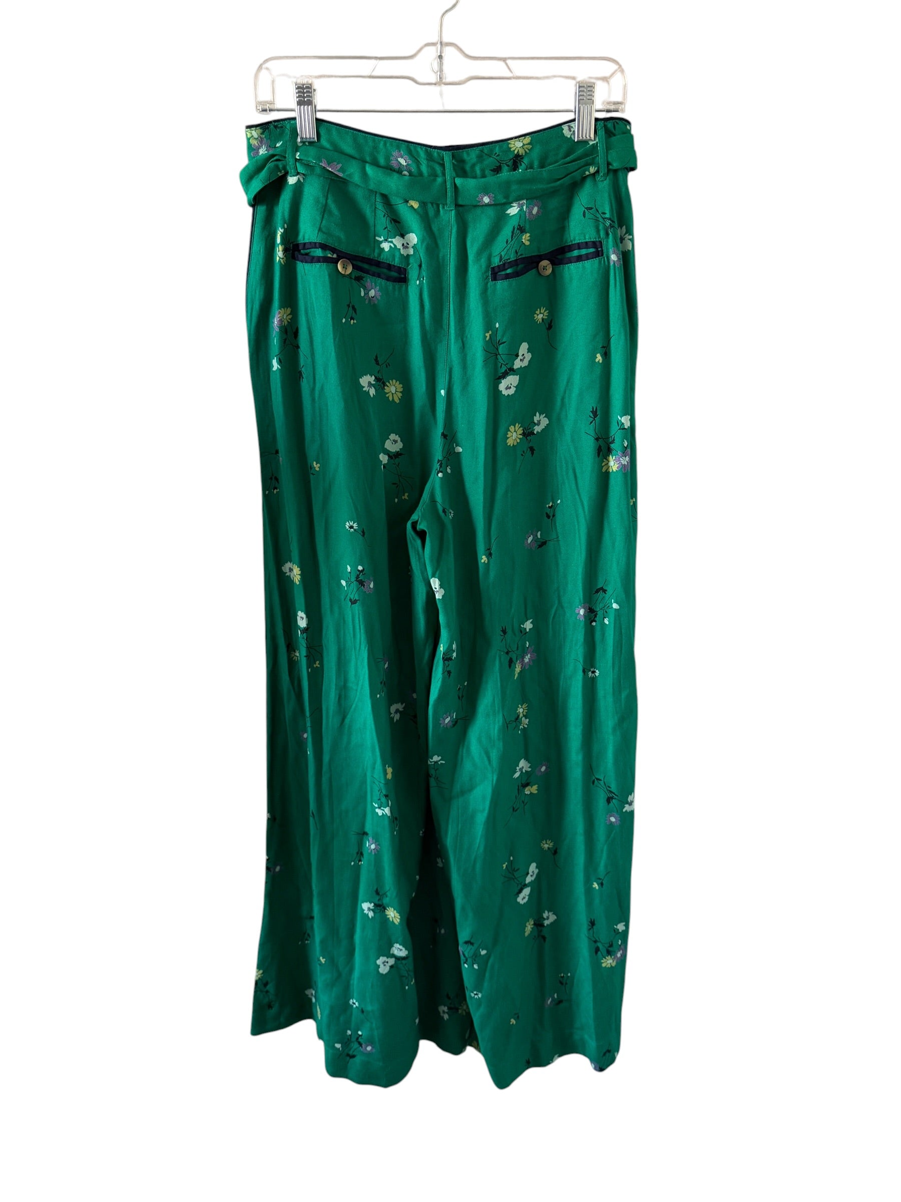 Green floral-patterned pants on a hanger against a white background