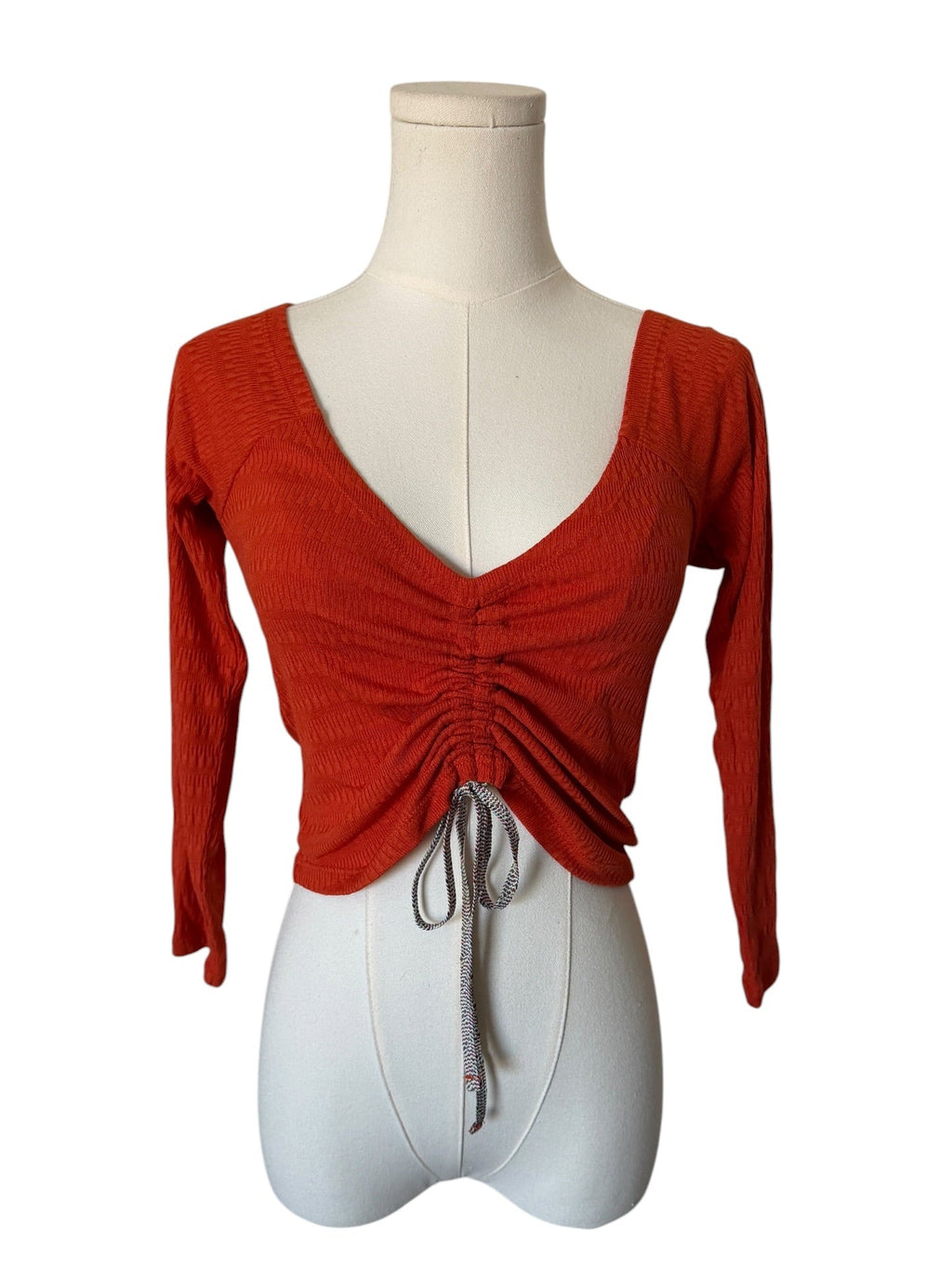 Red long-sleeve top on a mannequin against a white background