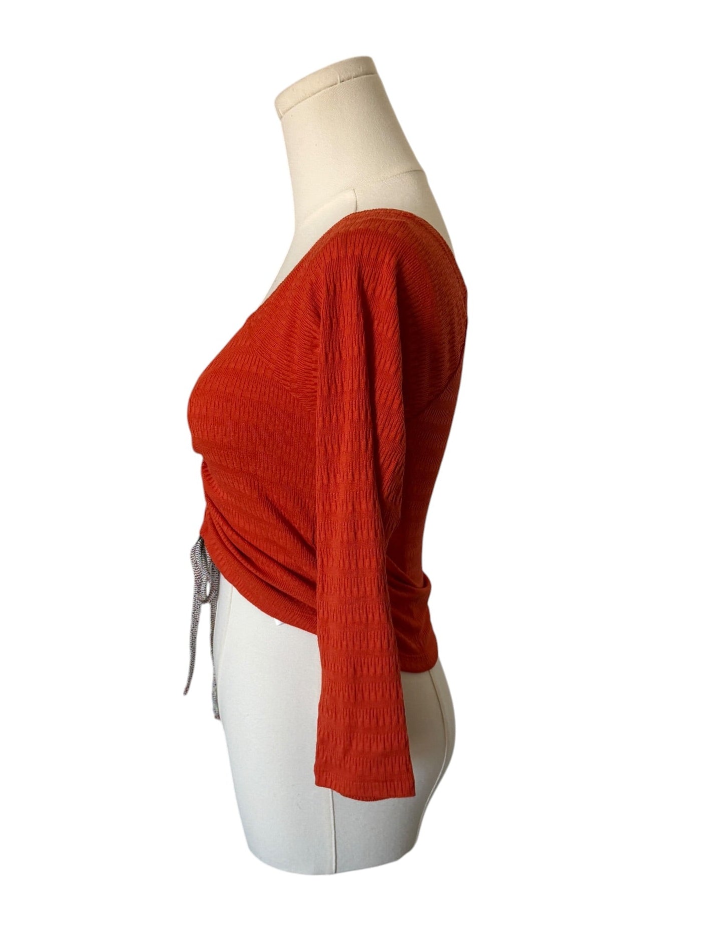 Red knitted cardigan on a mannequin against a white background