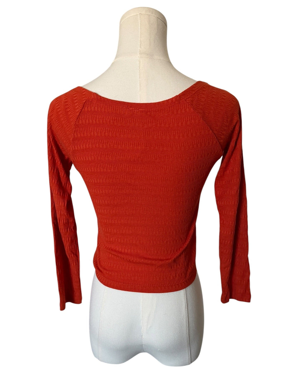 Red long-sleeve top on a mannequin against a white background