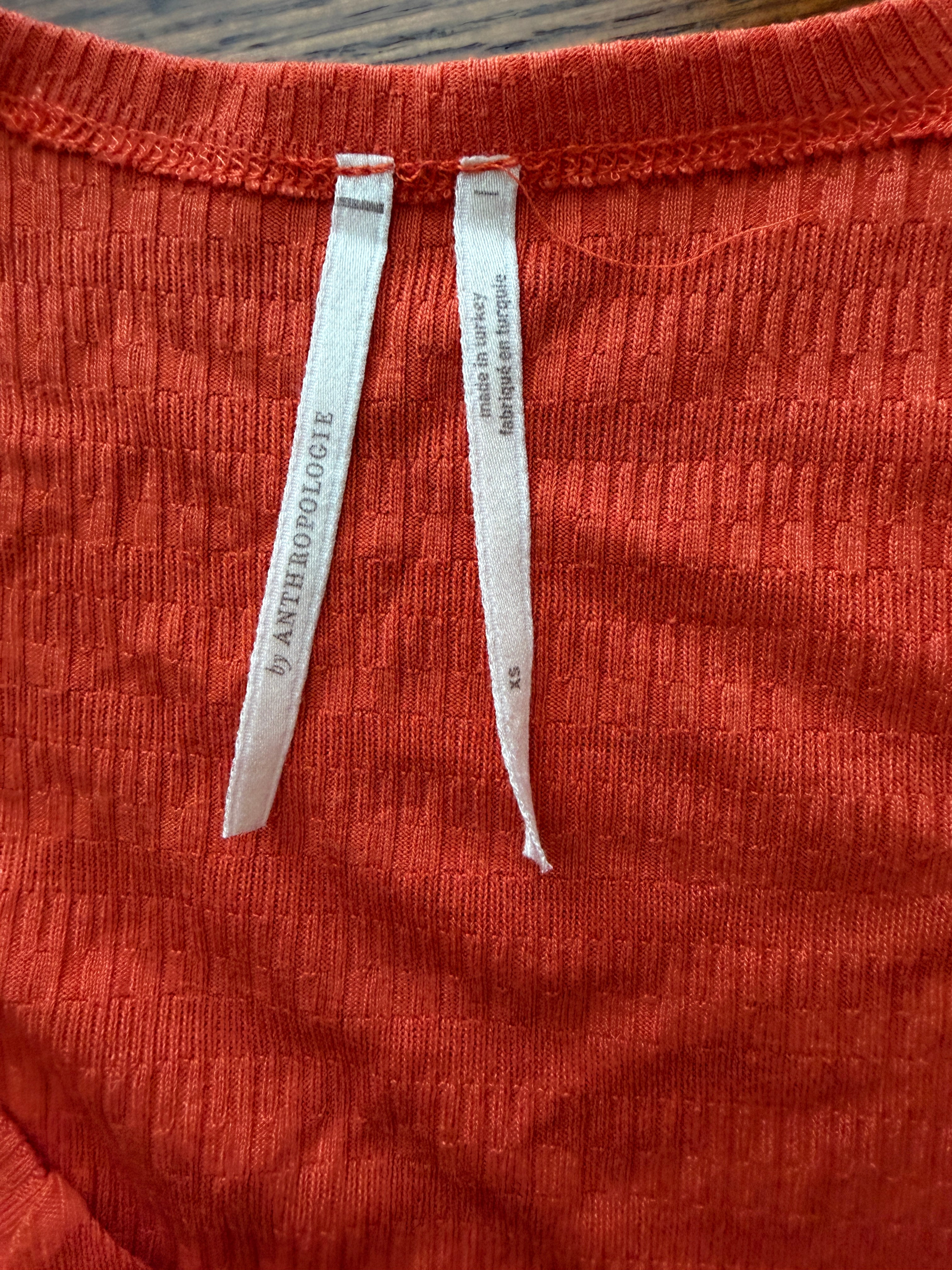 Close-up of red fabric with Anthropologie labels on a wooden surface