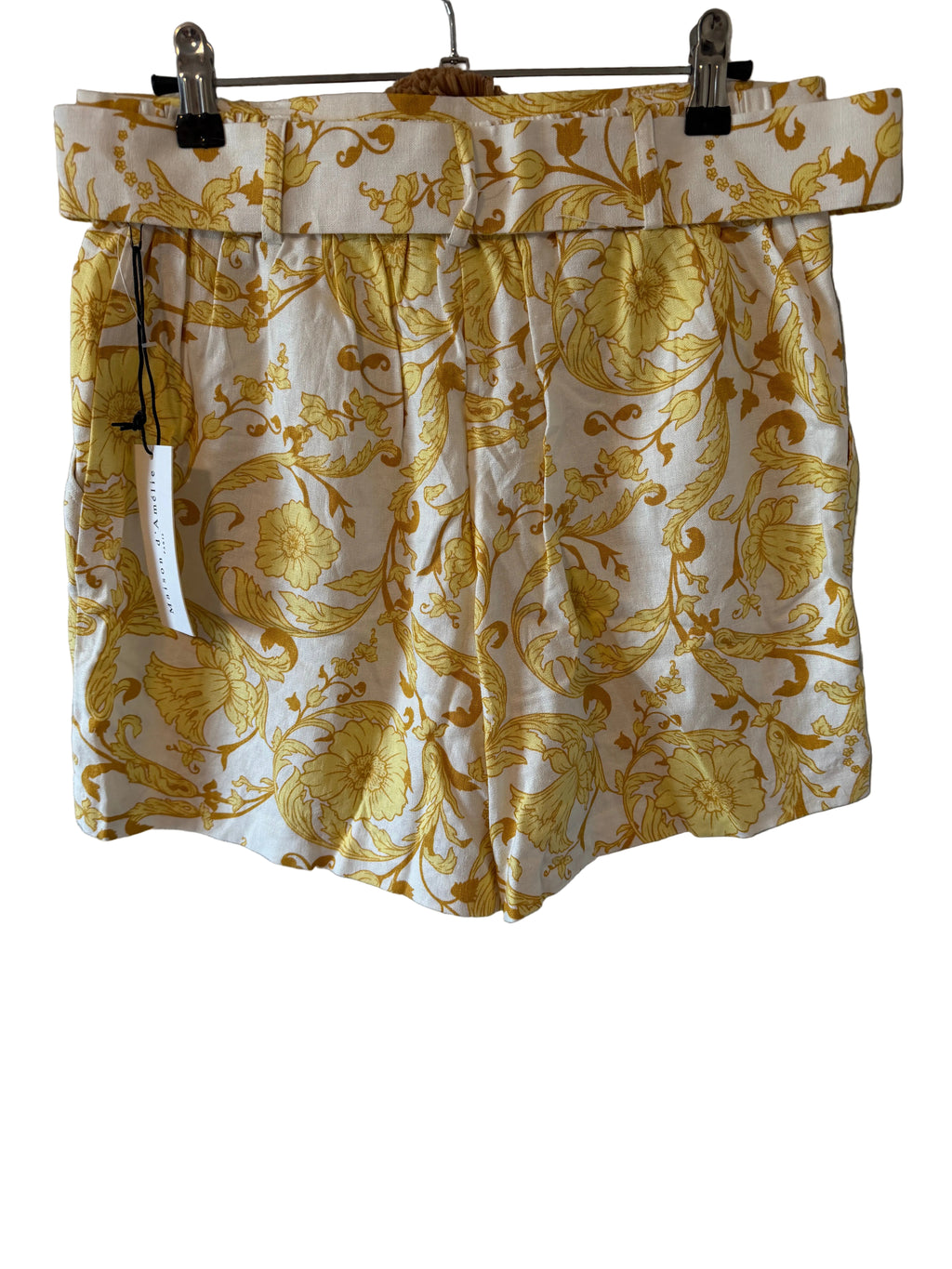 Yellow floral shorts hanging on a gray wall