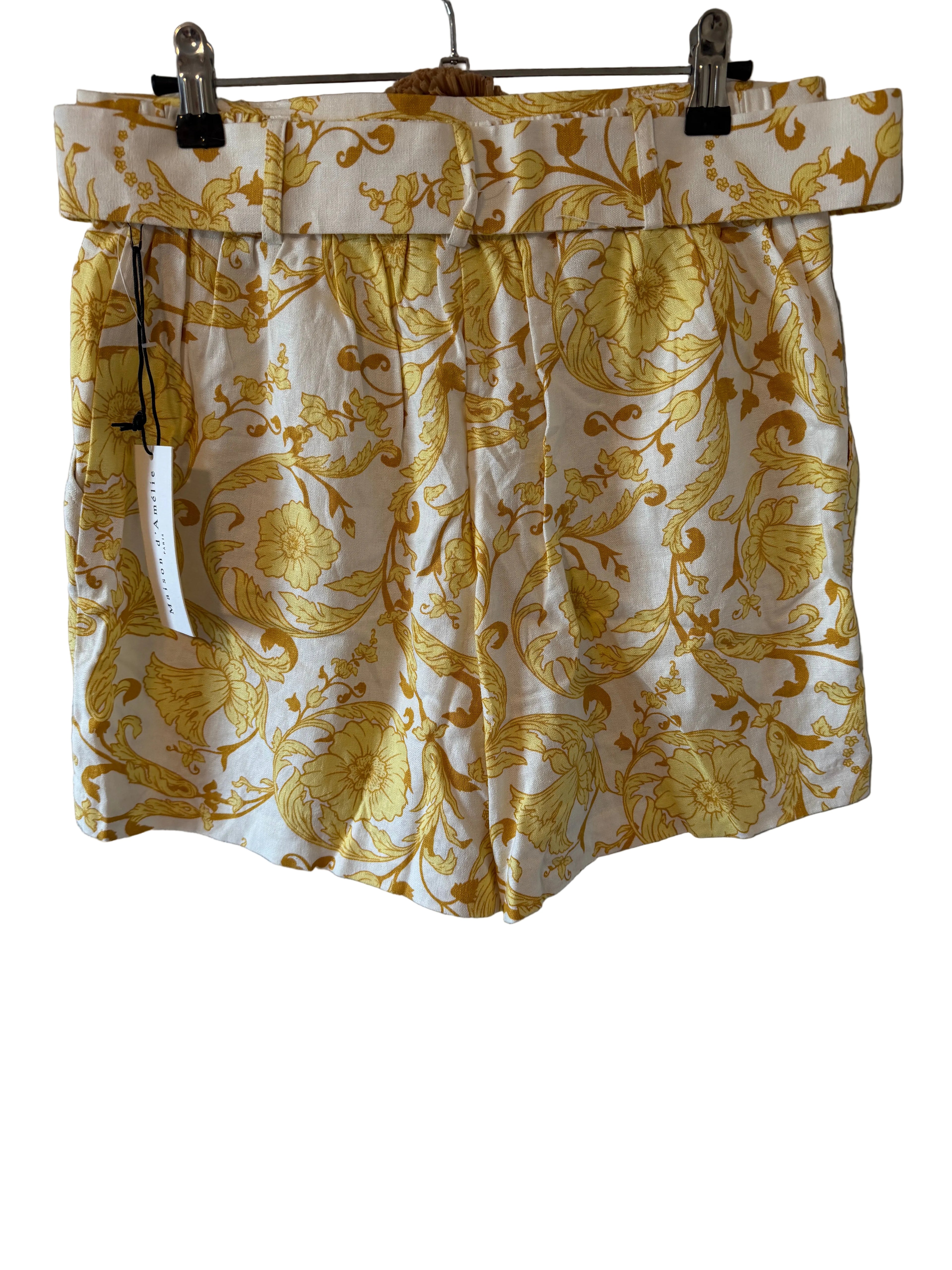 Yellow floral shorts hanging on a gray wall